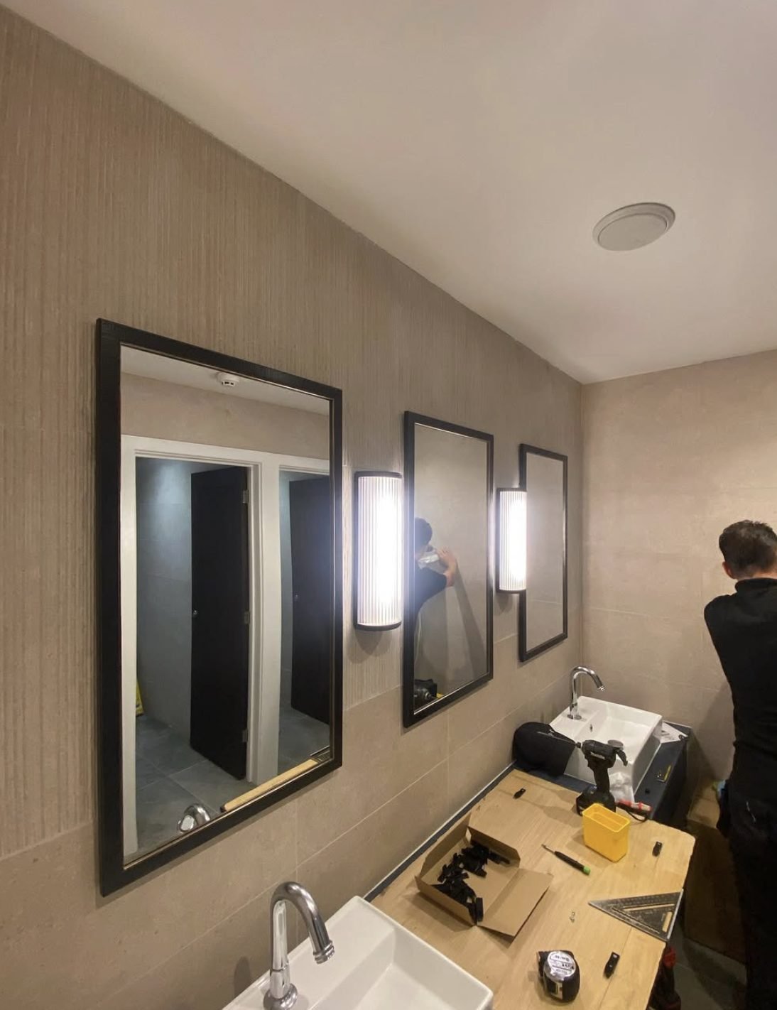 Wall lights and mirrors being fitted in a commercial washroom