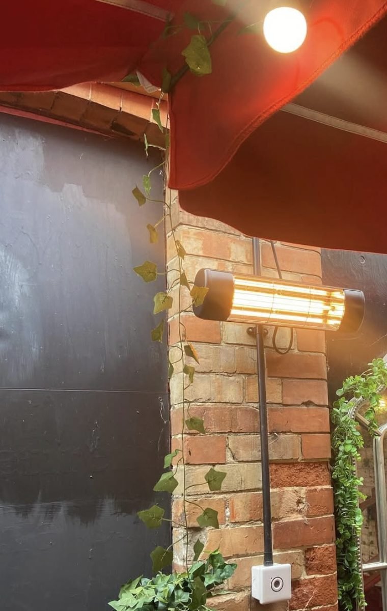 Infrared patio heater mounted on brickwork beneath an awning